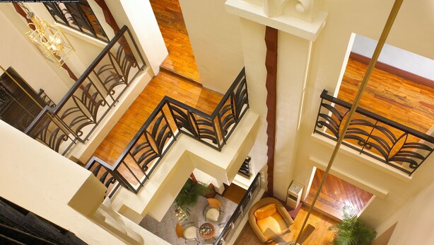 A spacious interior with a high ceiling, wooden flooring, and a central seating area with chairs and a table. - Miramar Hotel (Manila)