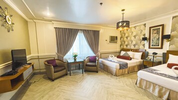 Quarto de hotel com duas camas, uma escrivaninha, uma cadeira, uma televisão e uma janela com cortinas.