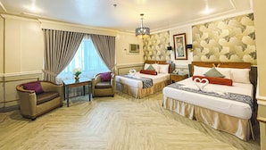 A hotel room with two beds, a sofa, a small table, and a chair. - Miramar Hotel (Manila)