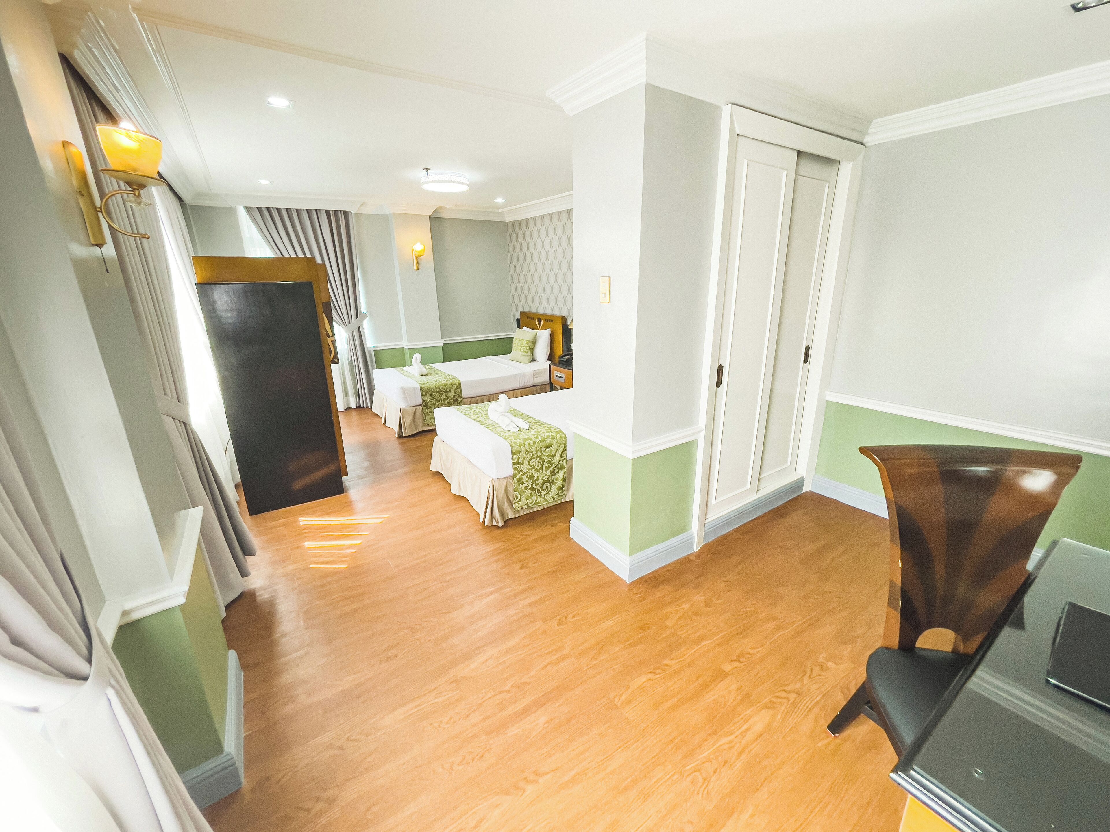 Une chambre d’hôtel avec deux lits, un bureau et une armoire.