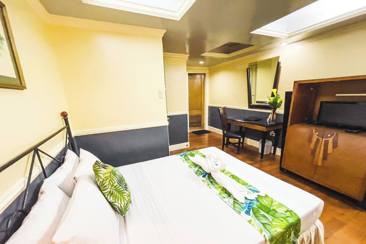 A hotel room with a bed, a desk, and a wardrobe.