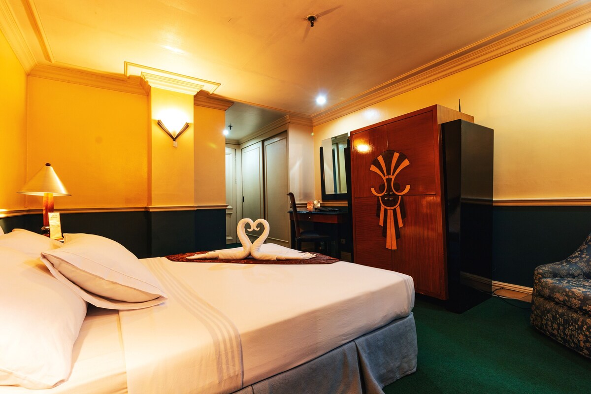 A hotel room with a bed, a desk, a wardrobe, and a chair.