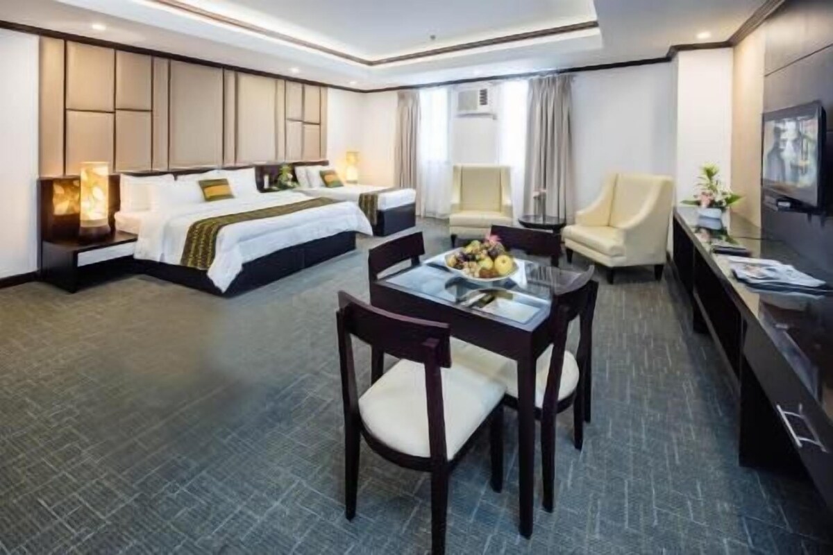Une chambre d’hôtel comprenant un lit, une table à manger avec des chaises, un téléviseur et un bureau.