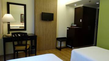 Una habitación de hotel con escritorio, silla, televisión, armario y dos camas.