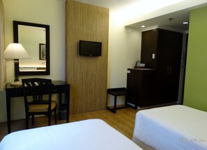 A hotel room with a desk, chair, TV, wardrobe, and two beds. - Hotel Fleuris Palawan (Puerto Princesa)