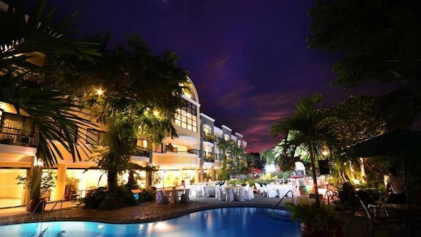 A hotel with a swimming pool, outdoor seating, and a well-lit facade. - Hotel Fleuris Palawan (Puerto Princesa)