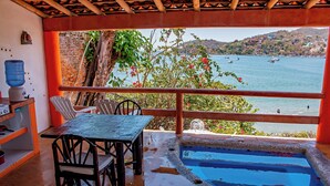 Un balcón con piscina, sillas y una mesa, con vista a un cuerpo de agua con barcos.