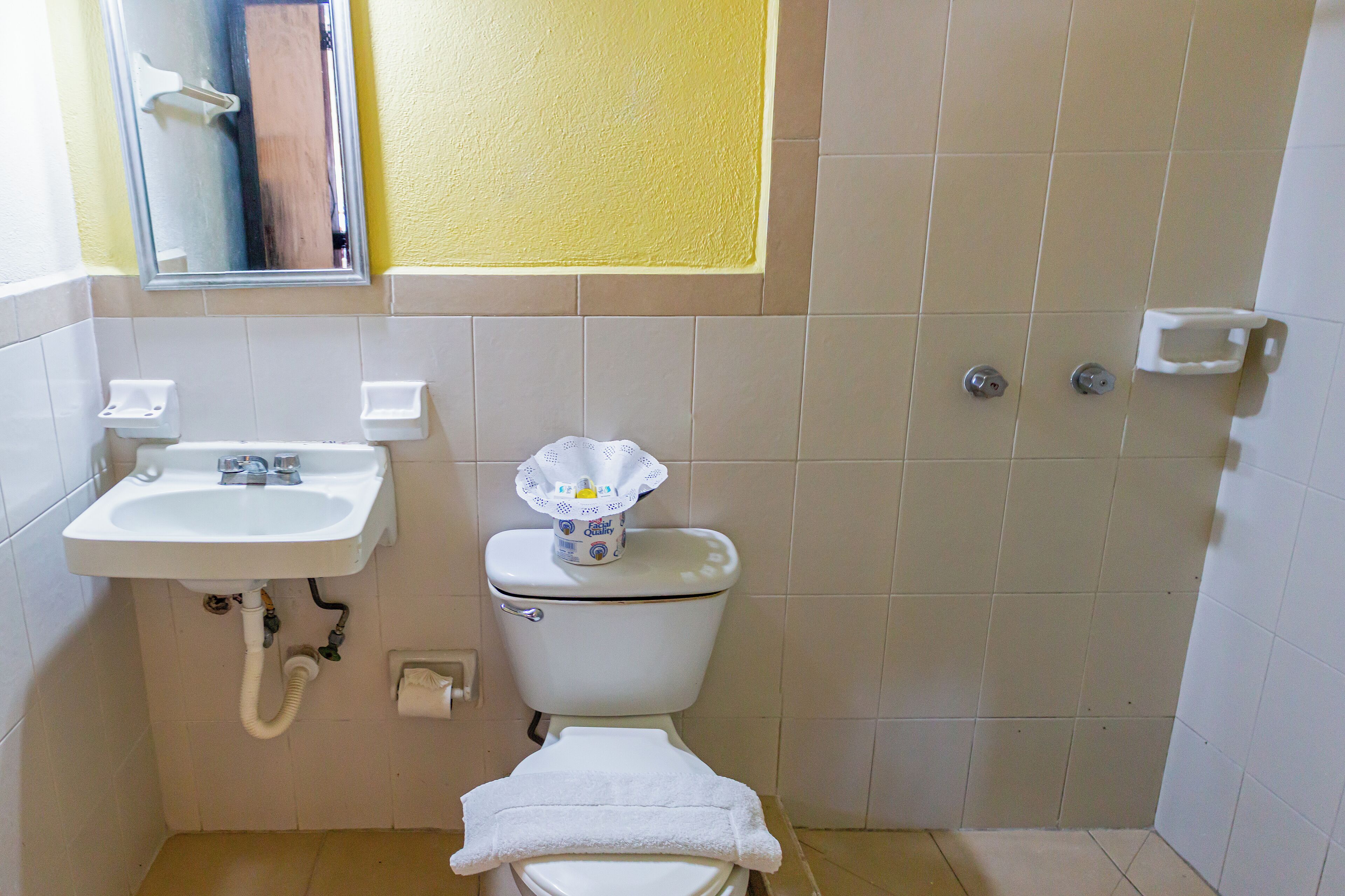 Ein Badezimmer mit weißem Waschbecken, Toilette und einem Spiegel über dem Waschbecken.