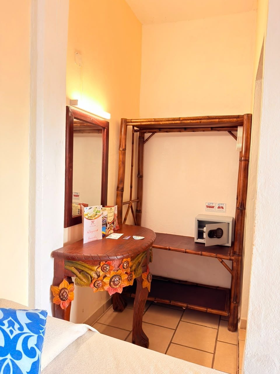 Une petite pièce avec un lit superposé en bois, une petite table recouverte d’une nappe à motifs floraux et un radiateur fixé au mur.