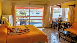 Habitación de hotel con una cama, una mesita, una silla y vistas al mar a través de un ventanal.