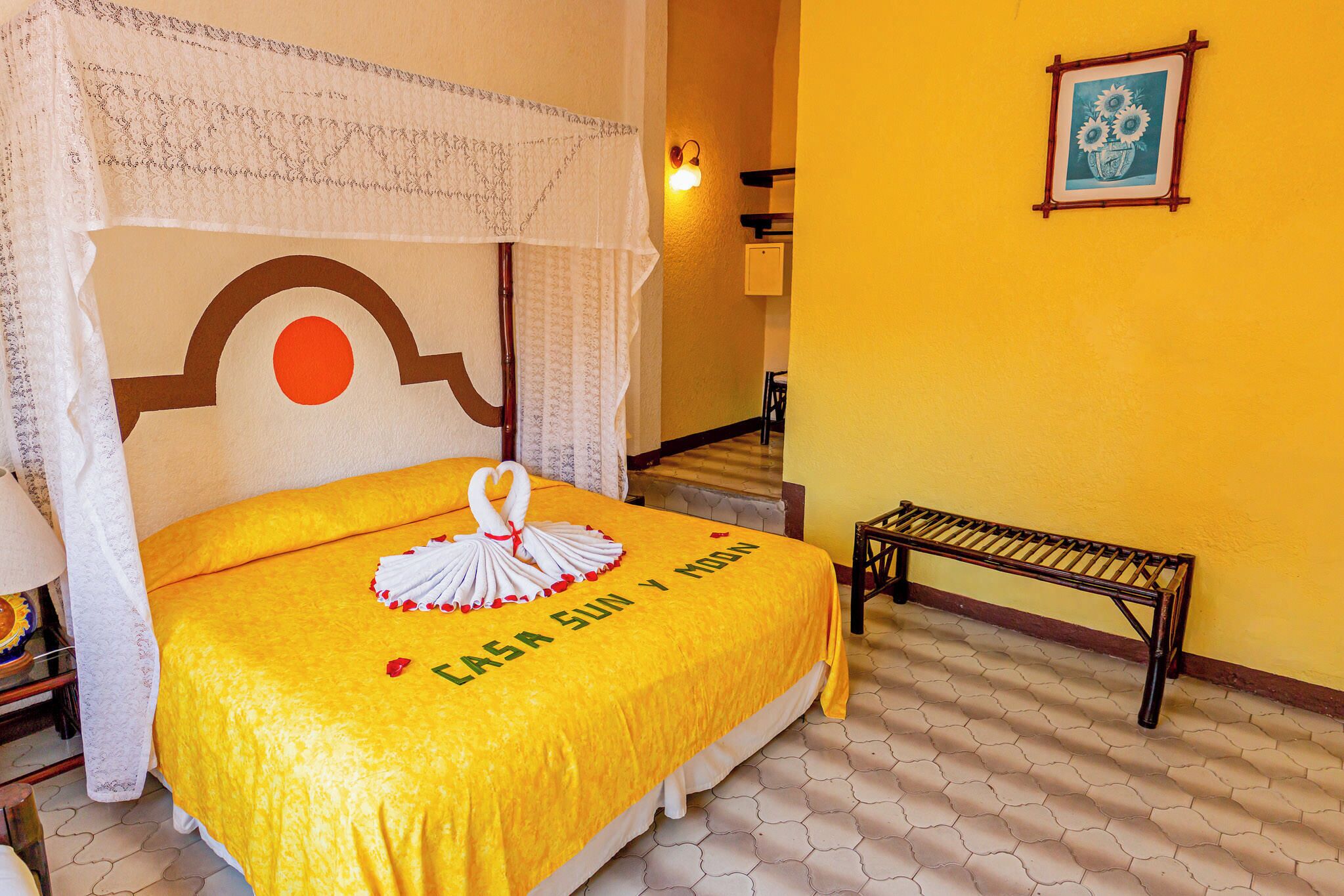 A bed with a yellow bedspread, a canopy, and a decorative swan.