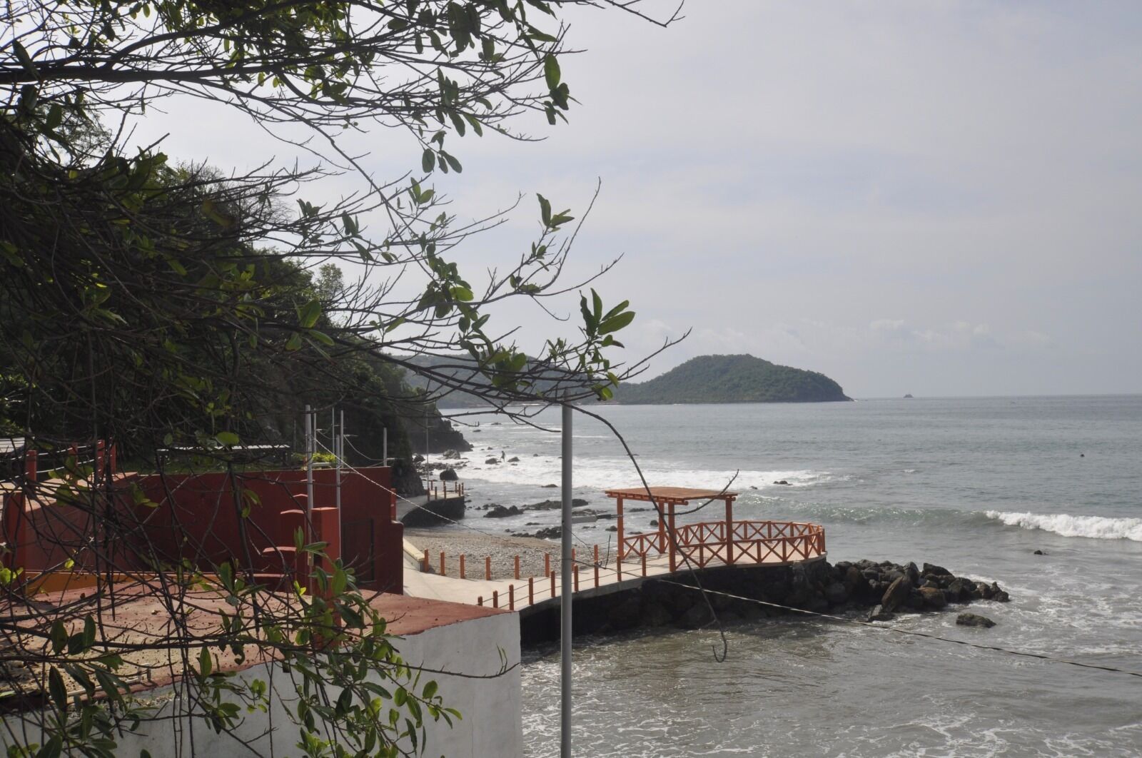 A coastal view with a pier, rocky shoreline, and a distant island.