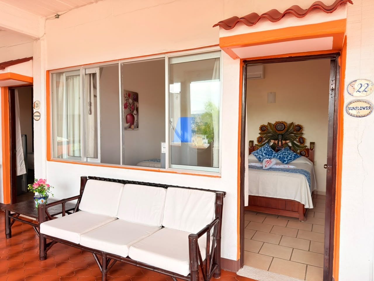 A room with a sofa, a bed with a decorative headboard, and a window with curtains.