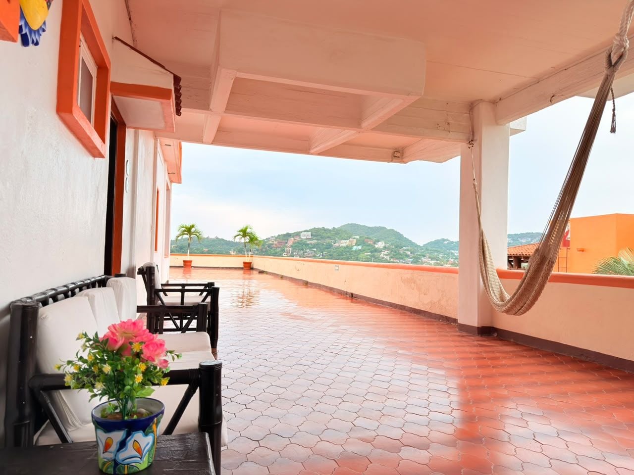 A covered outdoor seating area with a view of a hilly landscape.