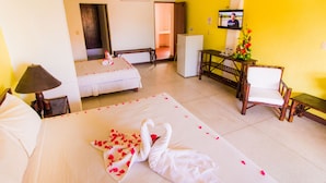 Una habitación de hotel con una cama, un escritorio, una silla, un televisor y un refrigerador pequeño.