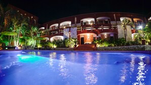 Un hotel con piscina, varios balcones y exuberante vegetación tropical.