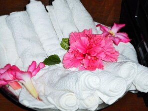 Un conjunto ordenado de toallas blancas con flores rosadas y hojas verdes.