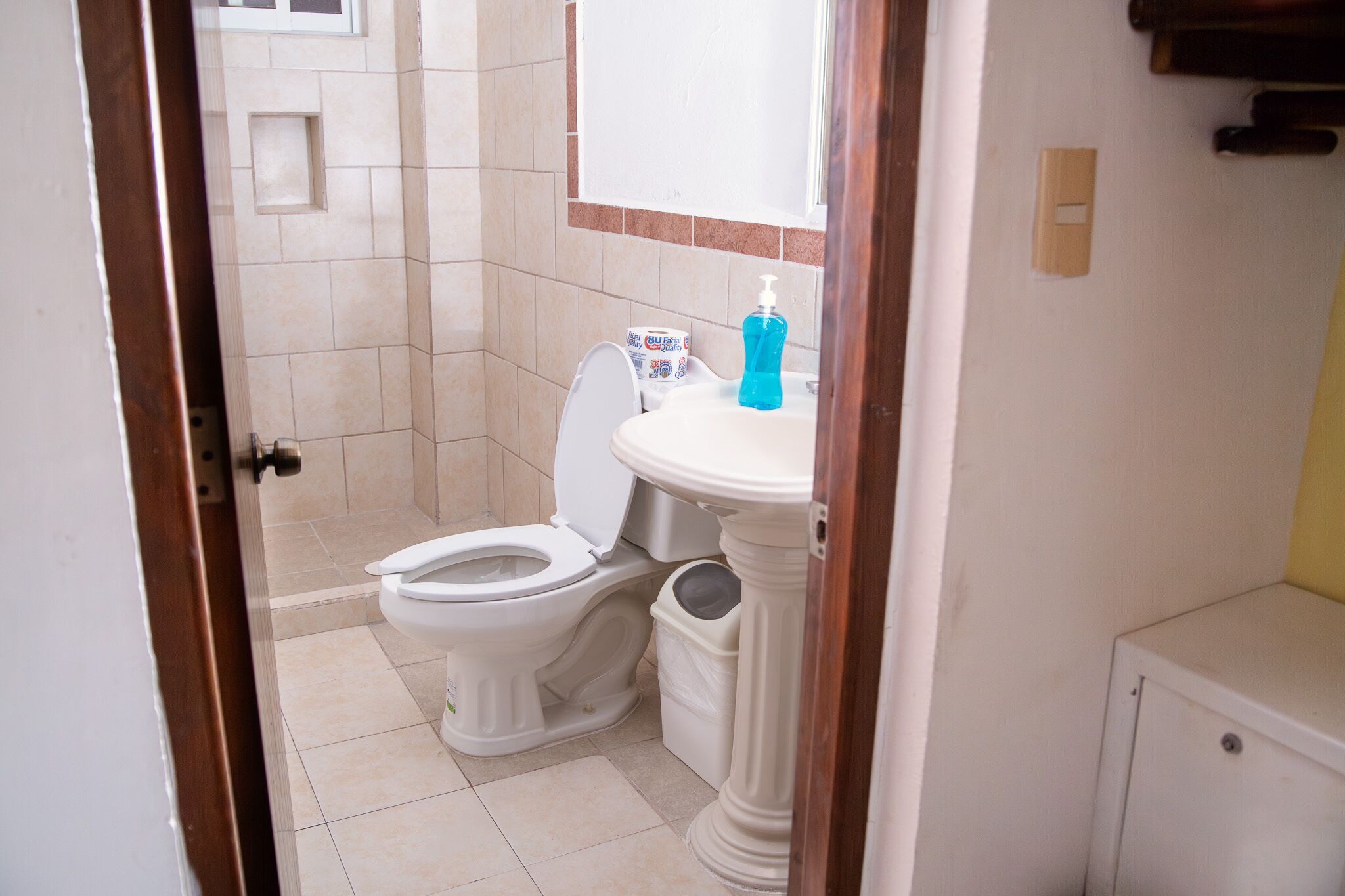 Une salle de bain équipée de toilettes, d’un lavabo et d’une poubelle.