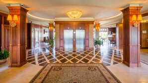 A hotel lobby with a checkered floor, a large chandelier, and wooden columns with lamps. - Panska Gora (Lviv)