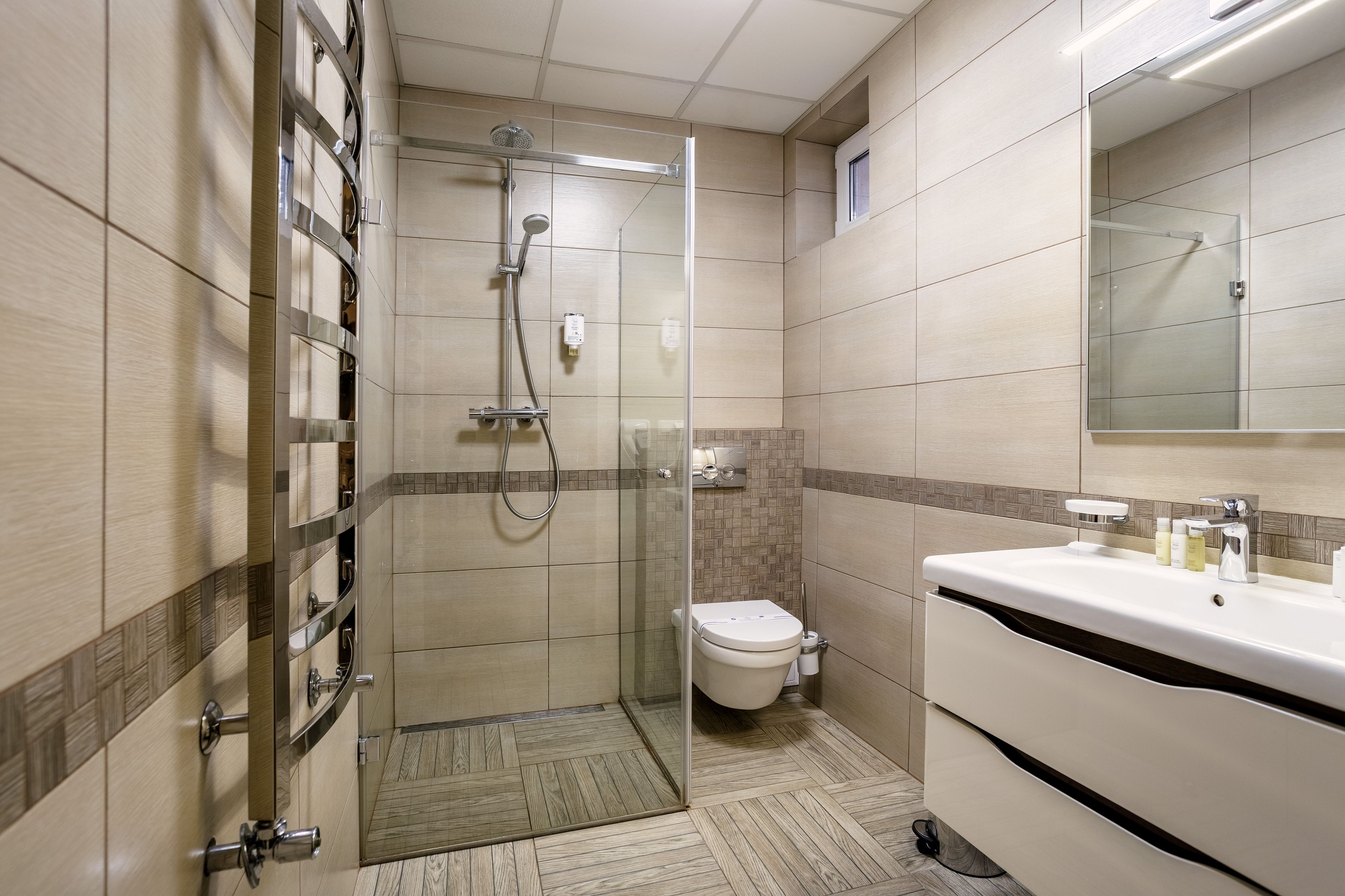 Een moderne badkamer met een glazen douchecabine, toilet en wastafel met toiletartikelen.