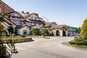 A residential area with a curved driveway leading to a gated entrance, surrounded by well-maintained hedges and trees. - Panska Gora (Lviv)