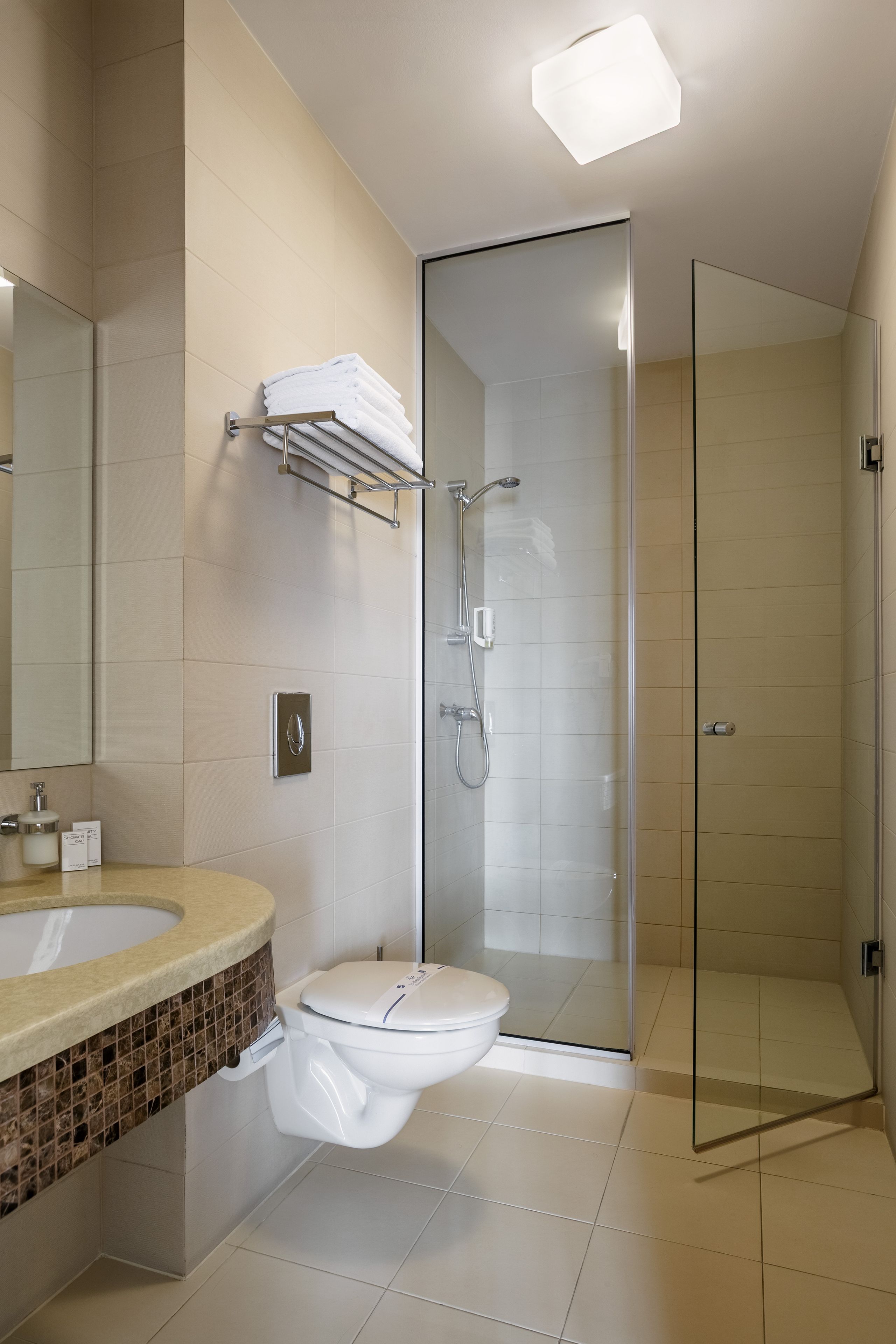 Un baño moderno con ducha envuelta en vidrio, inodoro y tocador con encimera de mármol.