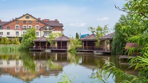 A tranquil lakeside setting with a traditional building and three wooden gazebos. - Panska Gora (Lviv)