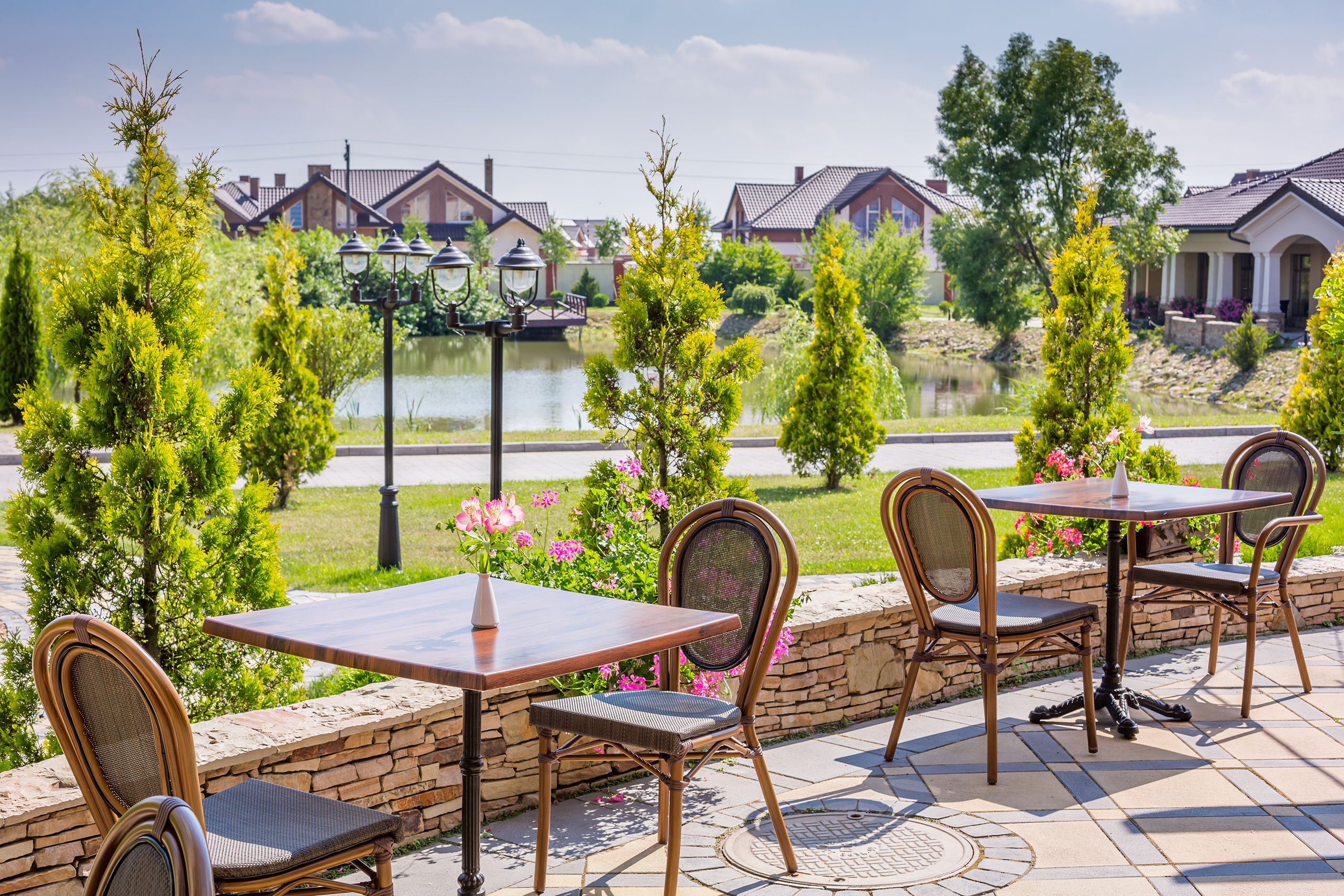 An outdoor patio with a table and chairs, a stone wall, and a view of houses and a body of water.