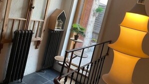Una escalera con barandilla de metal negro, un radiador fijado a la pared y una lámpara colgante.