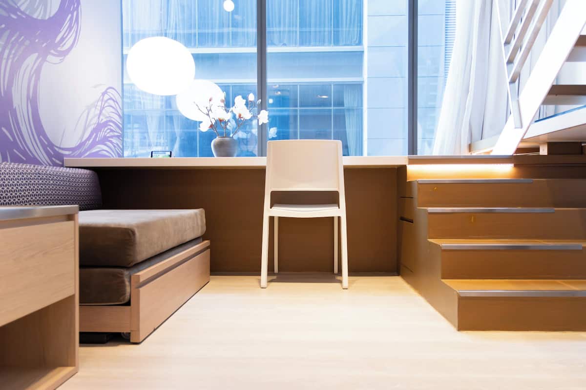 A modern, compact living space with a sofa, a desk, and a chair.