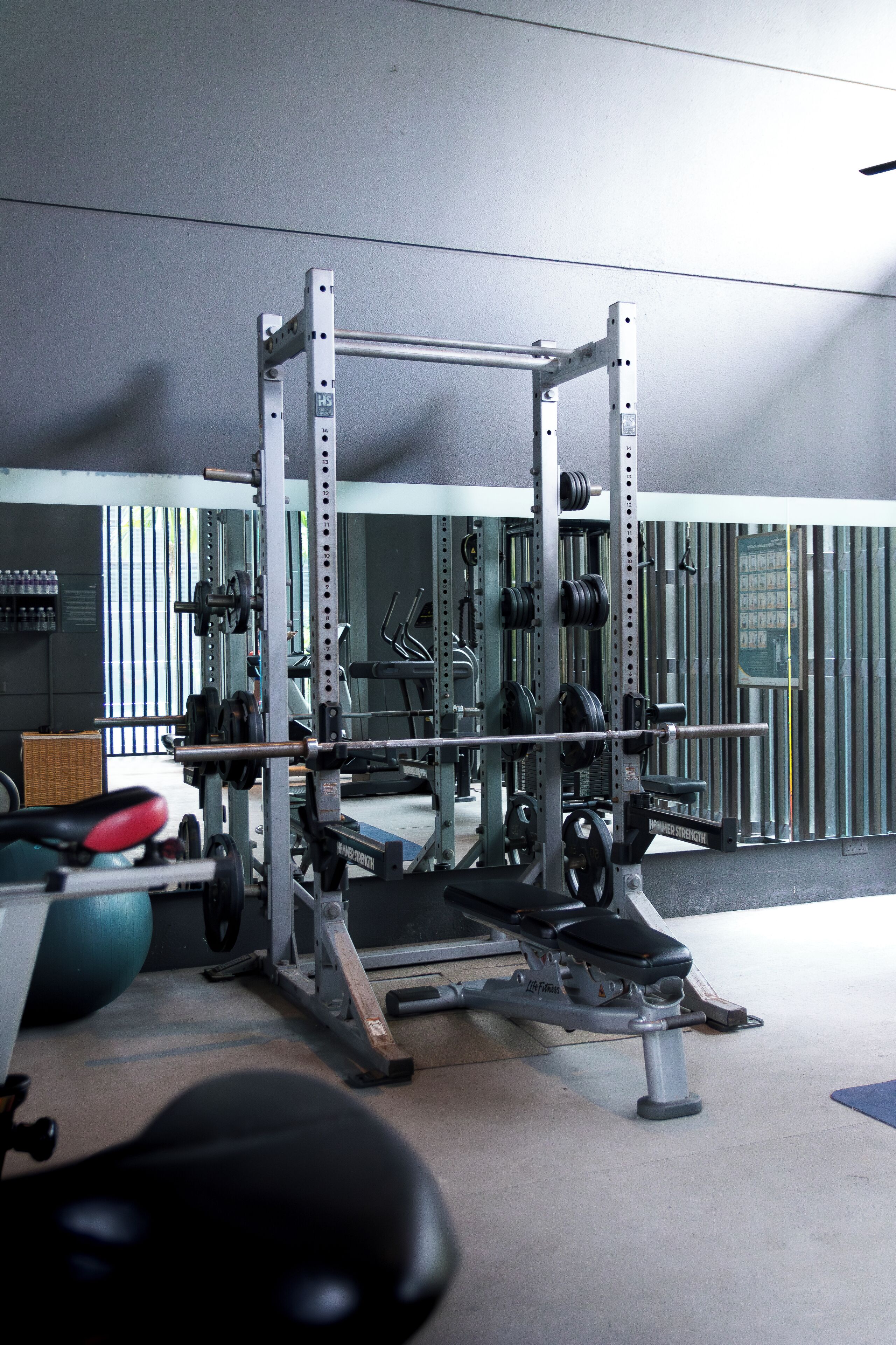 Une salle de sport équipée de matériel de musculation, de tapis de course et de ballons d’exercice.