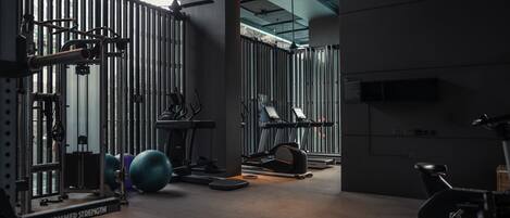 A gym with various exercise equipment, including a bench, treadmills, and weight machines.