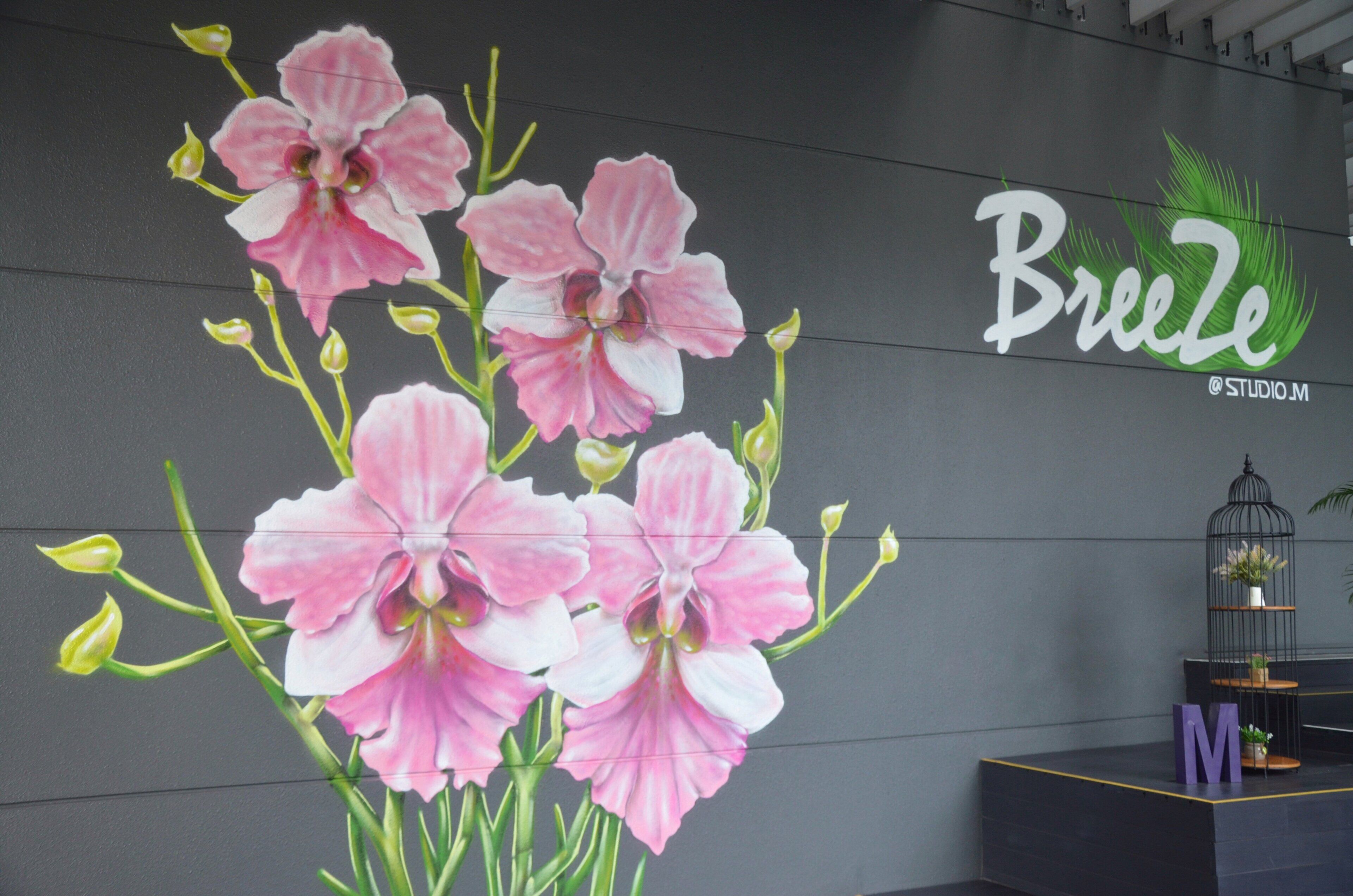 A wall with a mural of pink flowers and the word "Breeze" with a green palm leaf logo.
