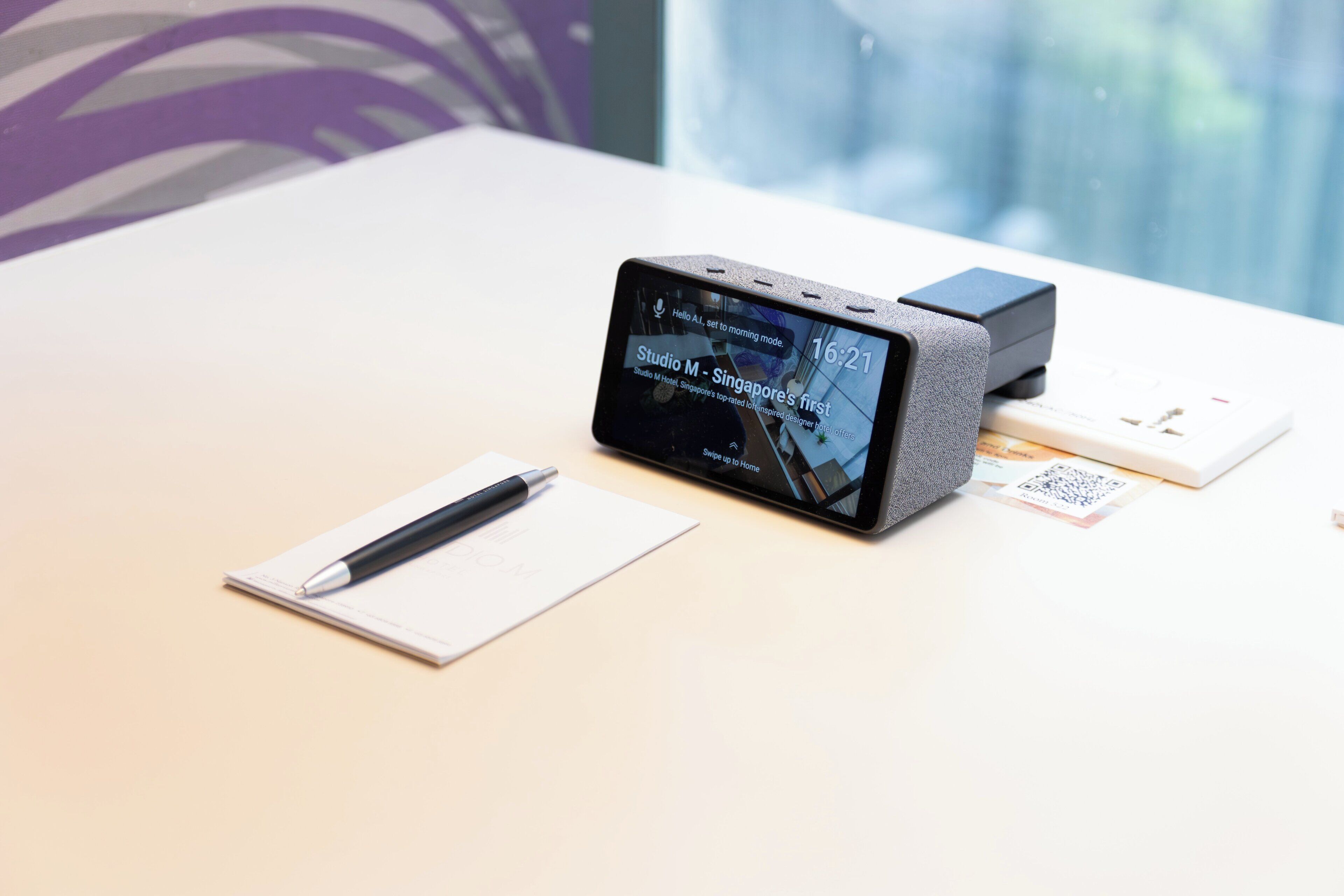 A smartphone on a table with a pen, a notepad, and a QR code.