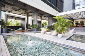 A modern outdoor pool area with seating and potted plants. - Studio M Hotel Singapore (Singapore)