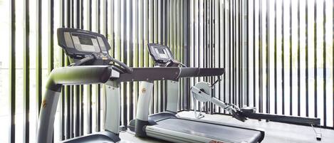 Un gimnasio con cintas de correr y equipo de ejercicio.