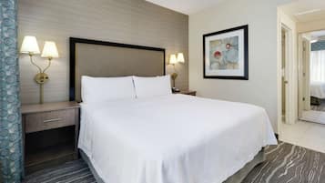 Habitación de hotel con una cama grande, dos mesitas de noche con lámparas, un cuadro enmarcado en la pared y una alfombra estampada.