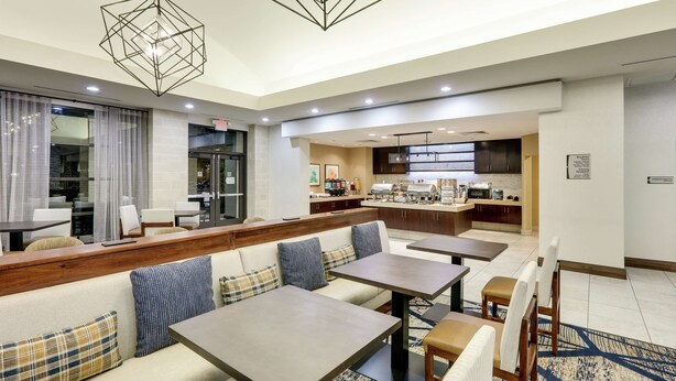 A modern hotel lobby with a seating area, a kitchenette, and a dining area. - Homewood Suites Dallas Allen (Allen)