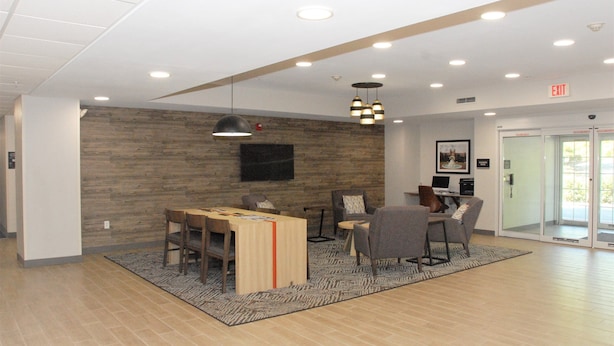 A modern lobby with a wooden wall, a reception desk, and a seating area with chairs and a table.