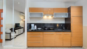 A modern kitchen with wooden cabinets, a black countertop, and a built-in microwave. - Appart’Hôtel La Villa Carnot Cannes (Cannes)