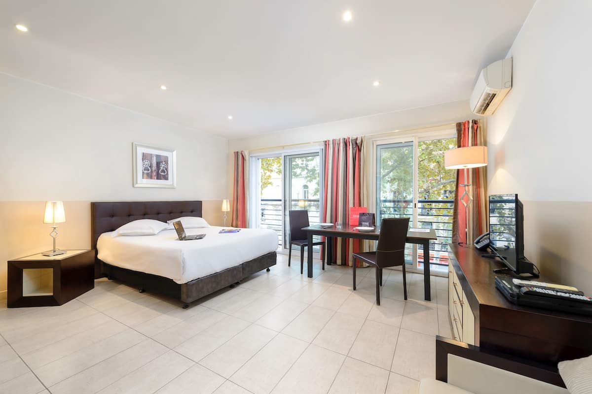 A hotel room with a bed, desk, chair, and a window with curtains.