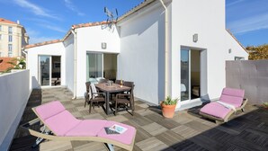 A rooftop terrace with a dining area, lounge chairs, and a potted plant. - Appart’Hôtel La Villa Carnot Cannes (Cannes)