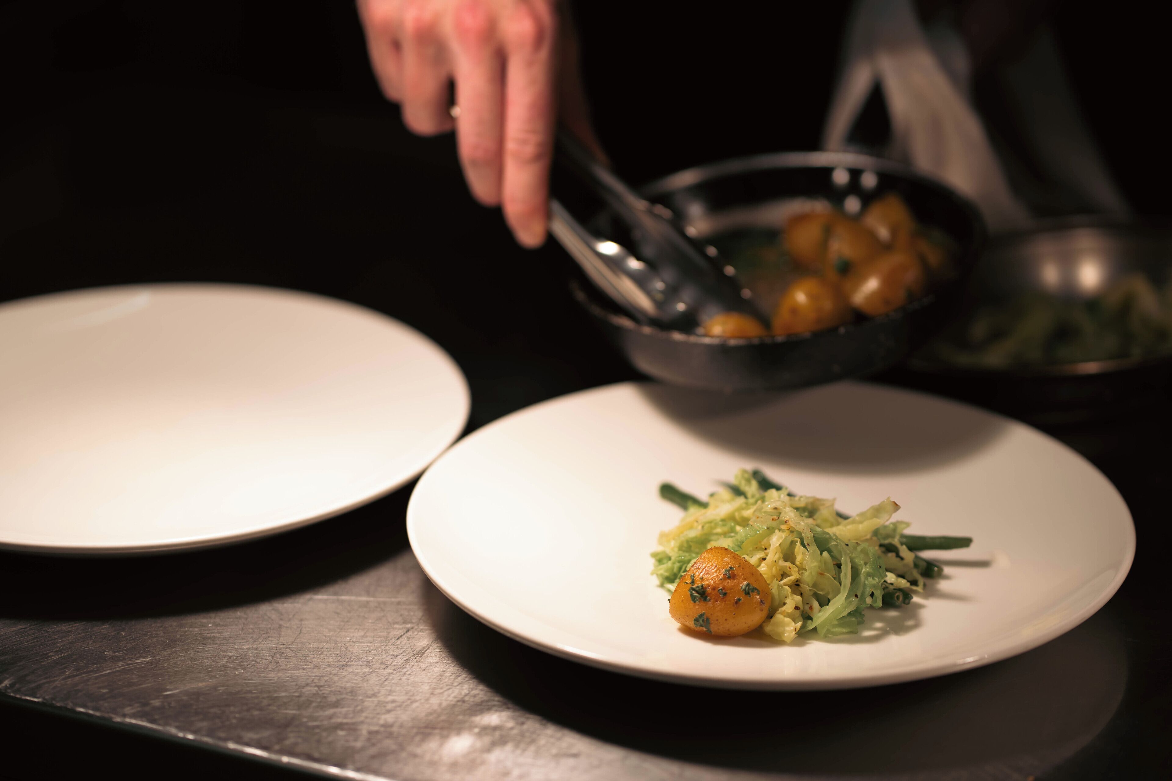A dining table with a plate of food and a bowl of vegetables.