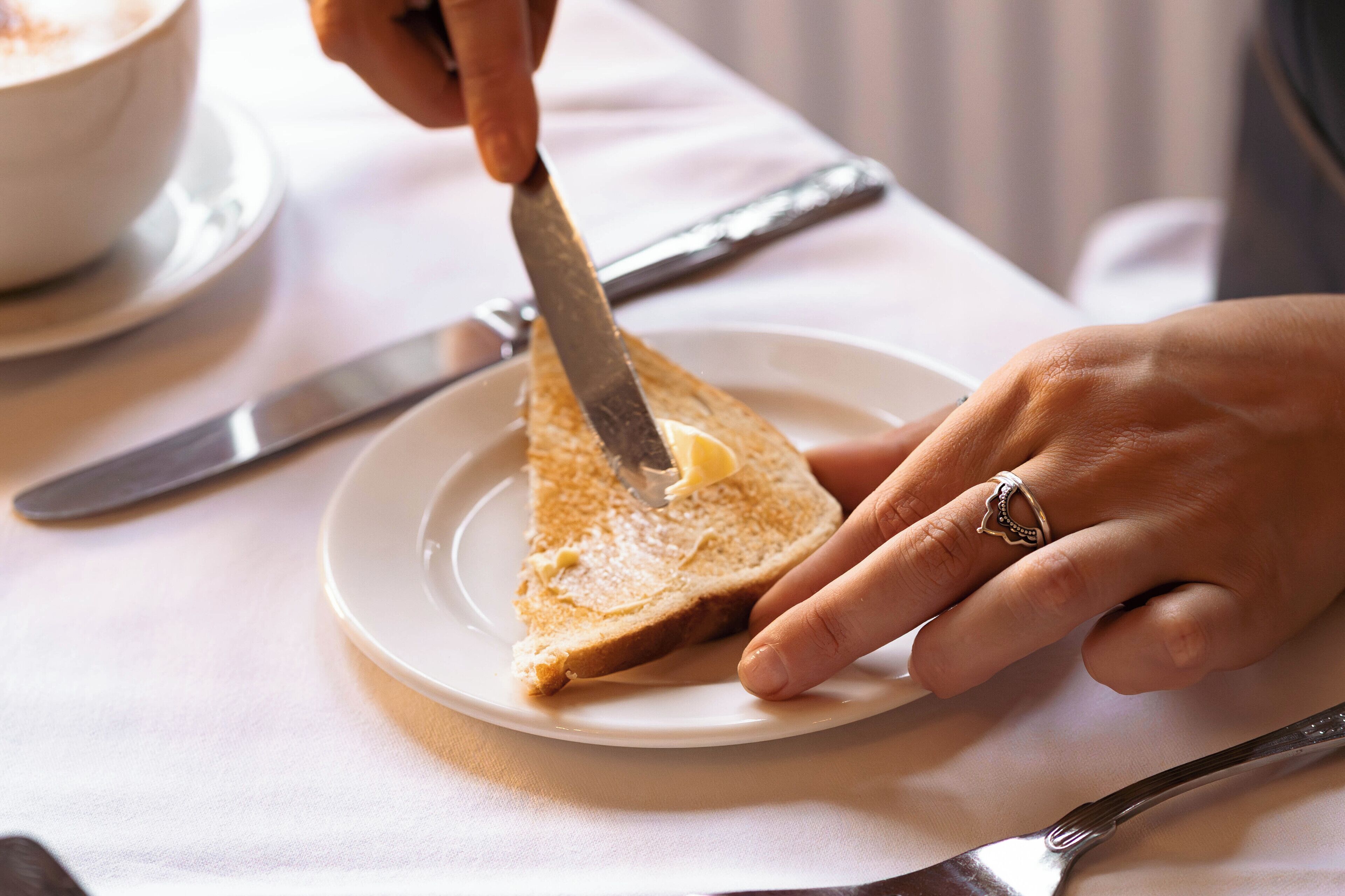A person spreading butter on toast on a plate.