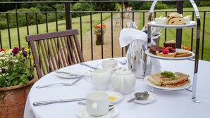 A table set for a tea service with a tiered dessert stand, a pitcher, cups, and a chair. - Classic Lodges Grinkle Park Easington (Saltburn-by-the-Sea)
