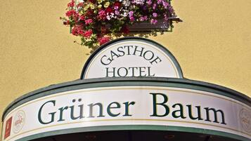 Une enseigne d’hôtel sur laquelle on peut lire « GASTHOF HOTEL » et « Grüner Baum ».