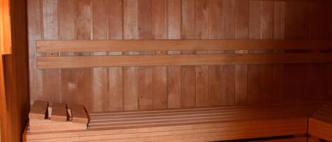 A sauna with wooden benches and a wooden wall.