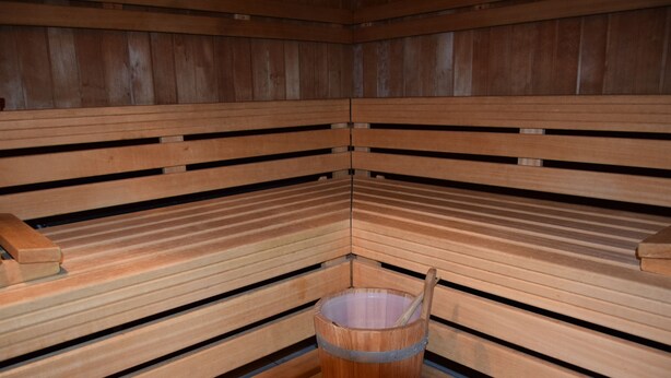 Uma sauna com bancos de madeira e um balde de madeira com alça.