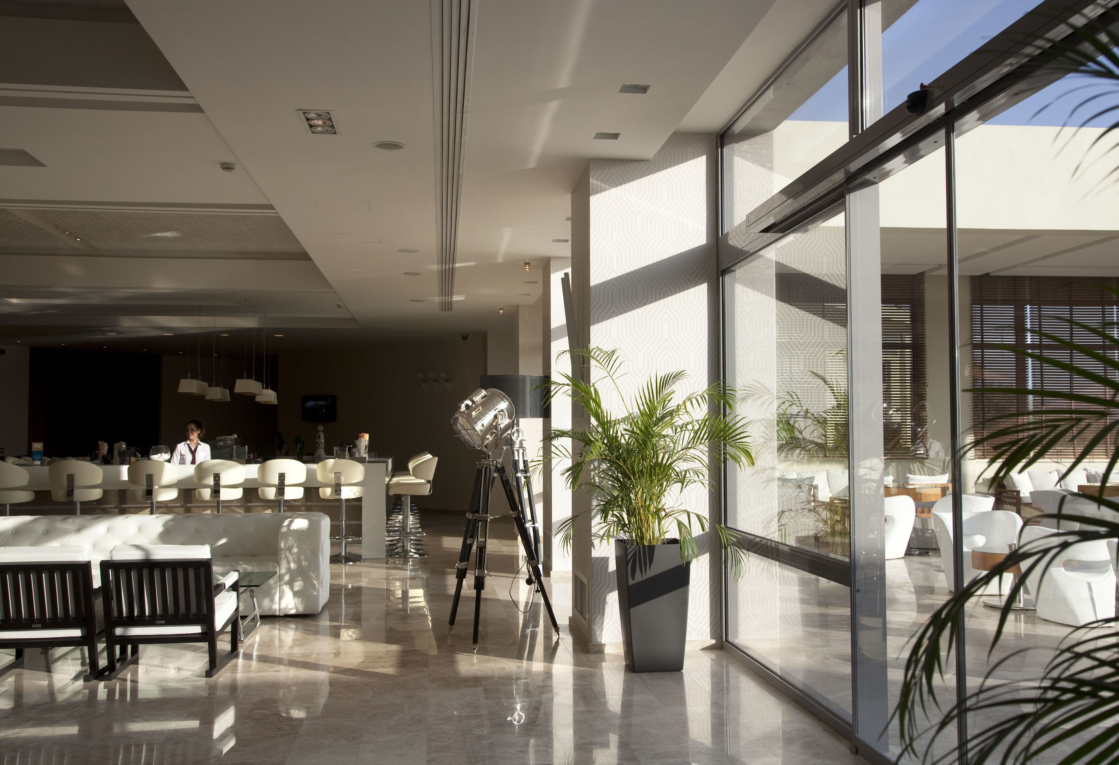A modern lobby with a reception desk, seating area, and a large window offering a view of the outdoors.