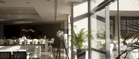 A modern lobby with a reception desk, seating area, and a large window offering a view of the outdoors.